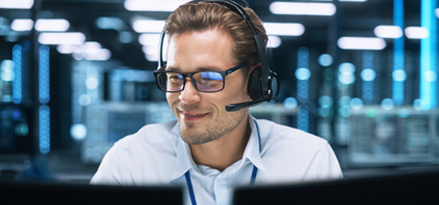 Person som sitter vid en helpdesk med ett headset på