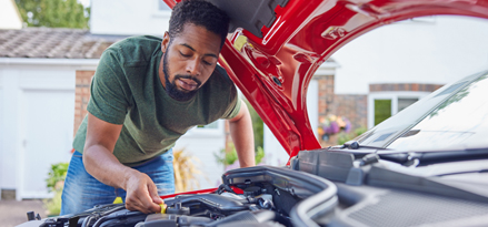 En person som reparerar sin bil med huven uppe